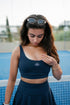 Be 180 Sports Bra - Midnight | Girl in Navy Sports Bra on Padel Court